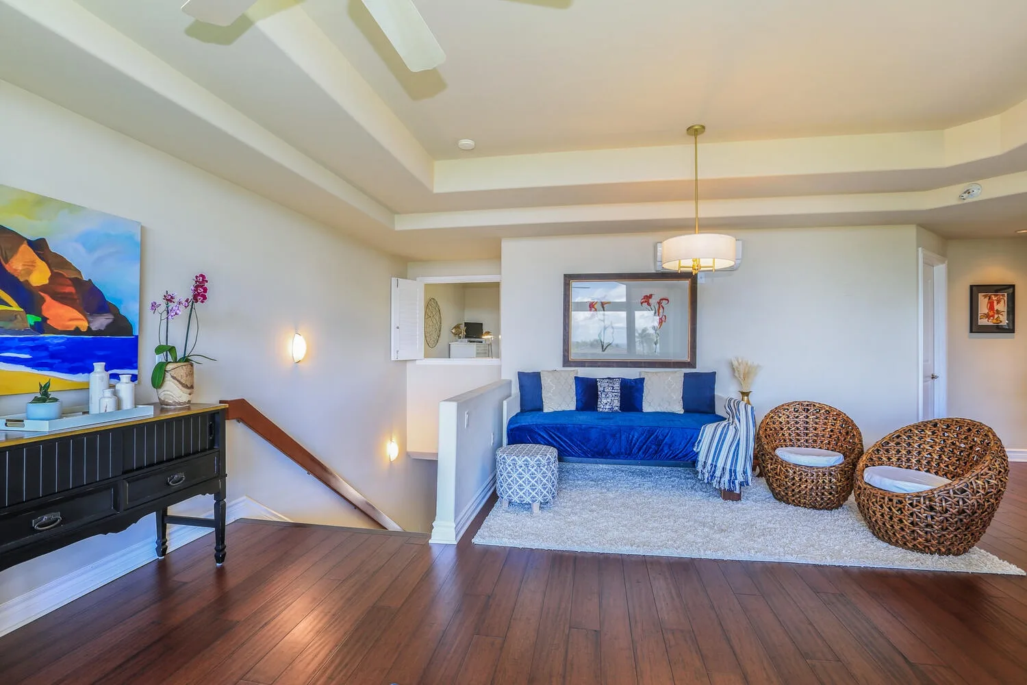 A bright living room features blue seating, a light rug, and woven chairs.