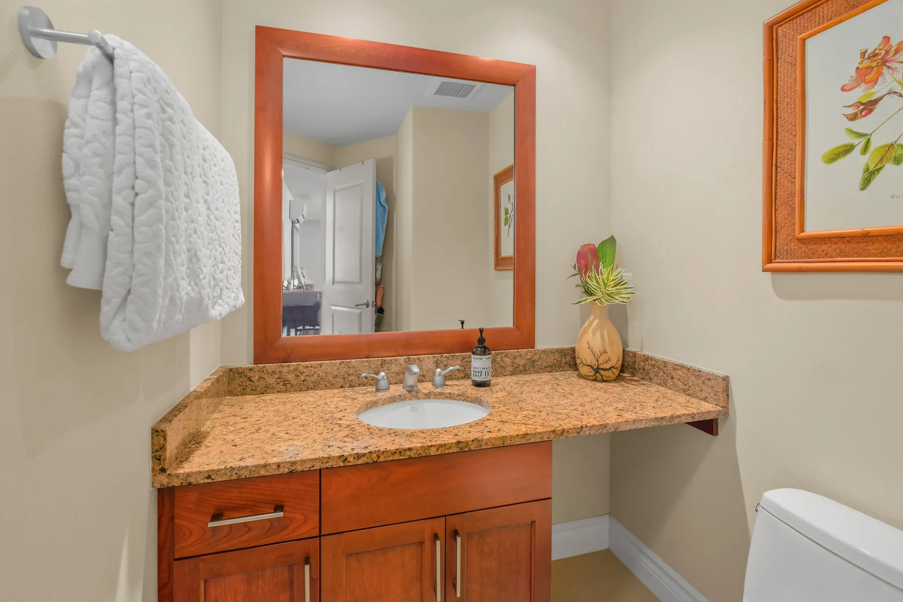 A bathroom vanity with a sink and mirror, beside a toilet.