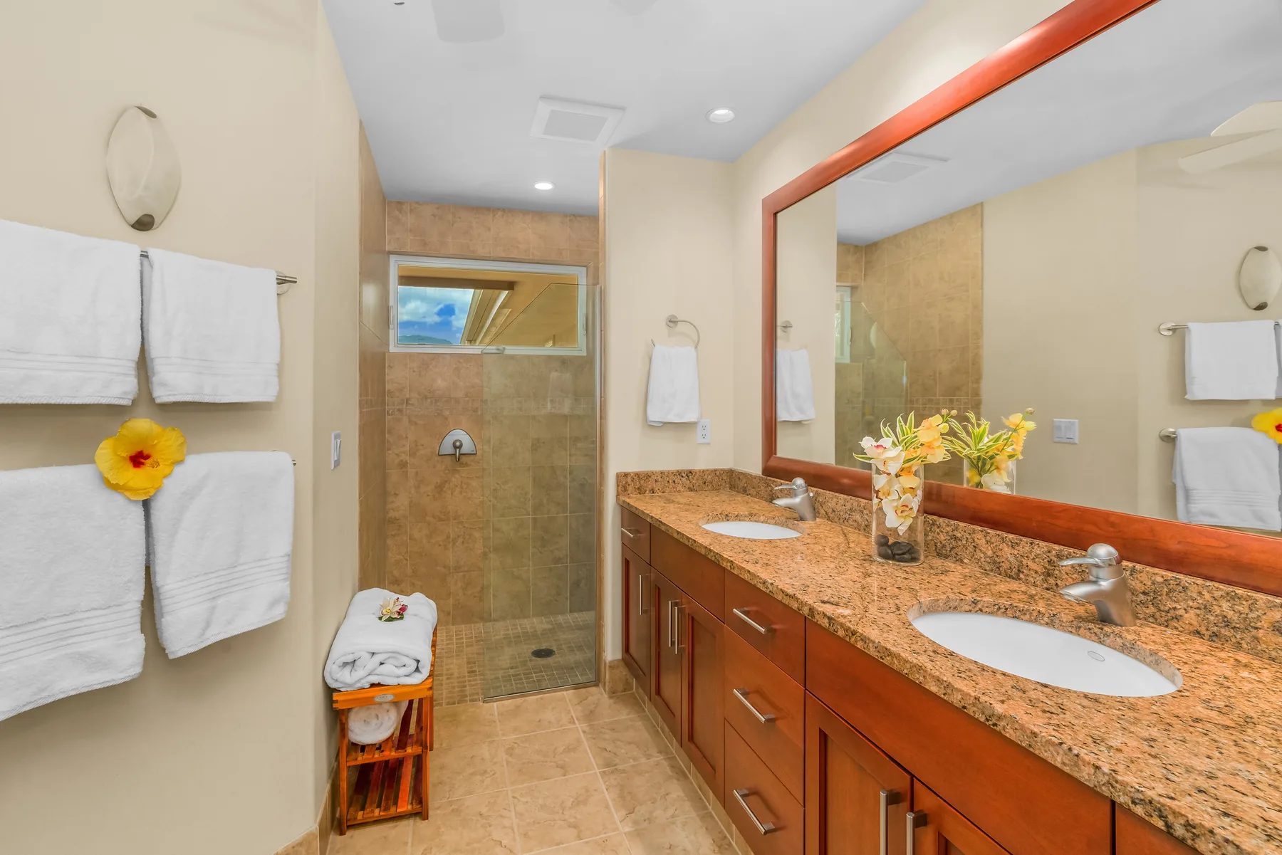 A bathroom vanity with a large mirror faces a glass shower.