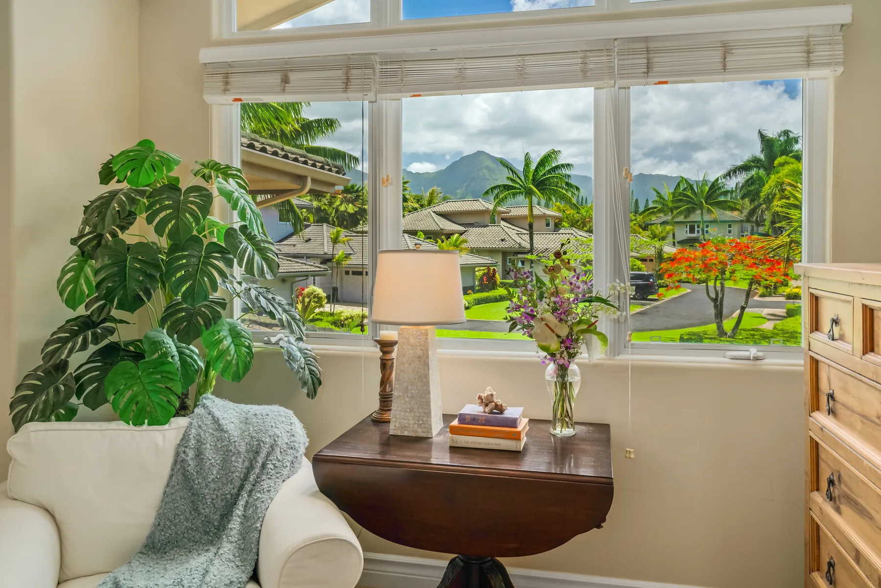 A bright sitting area with large windows overlooking tropical greenery.