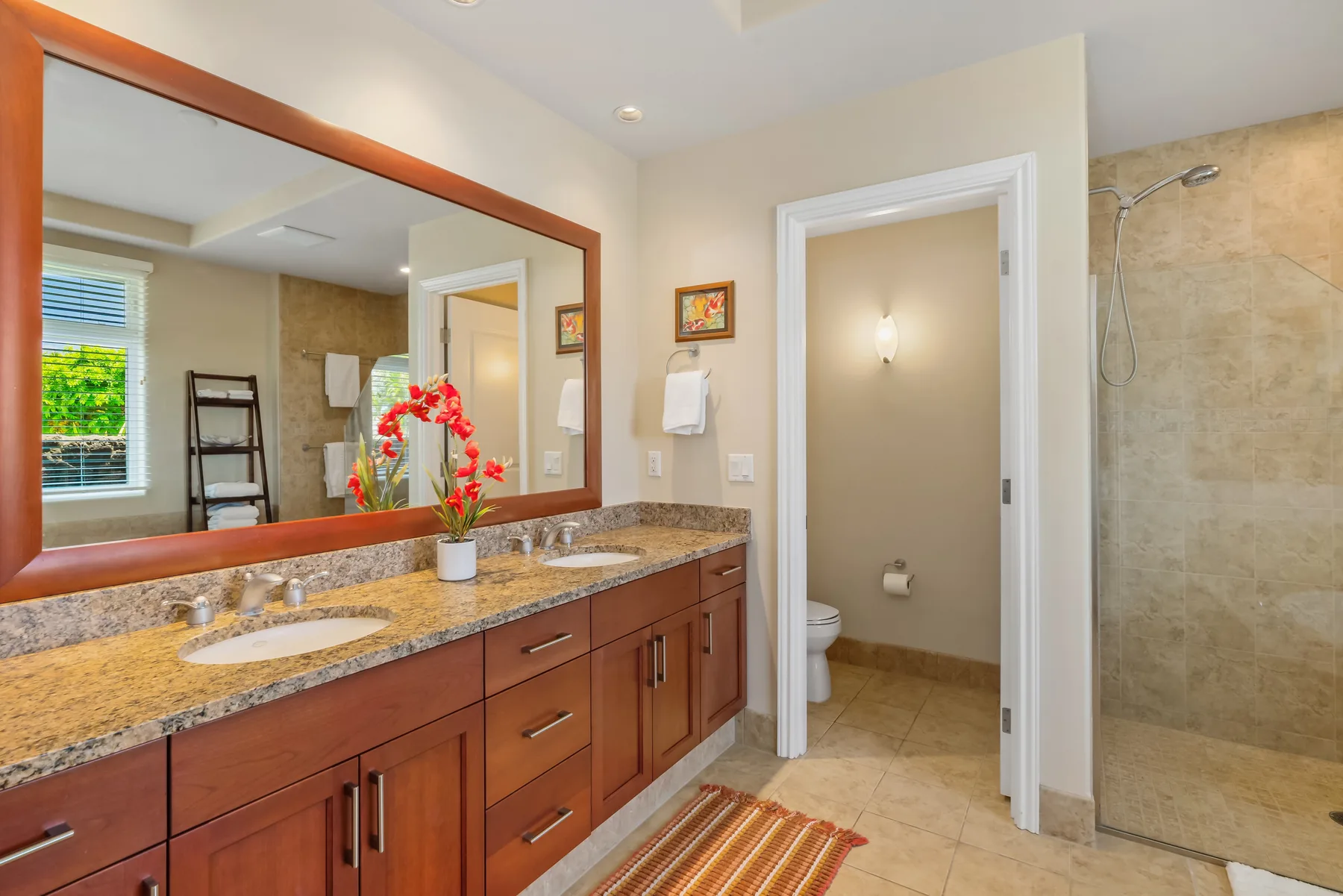 A bathroom vanity with a wide mirror sits beside an open doorway and shower.