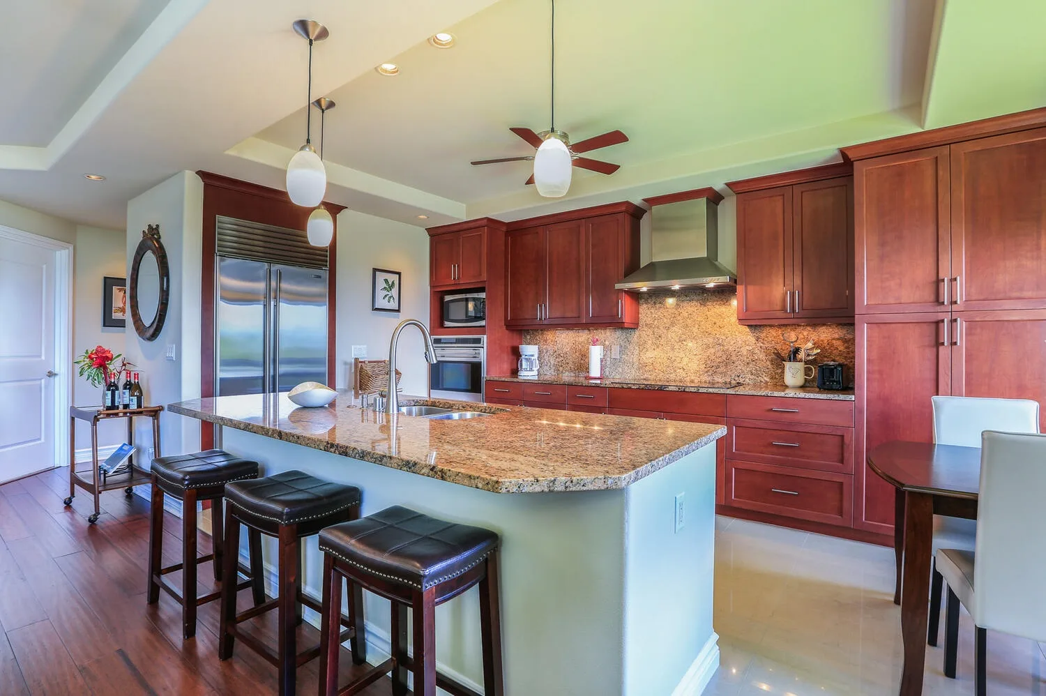 A kitchen with reddish wood cabinets and a large island with bar seating.