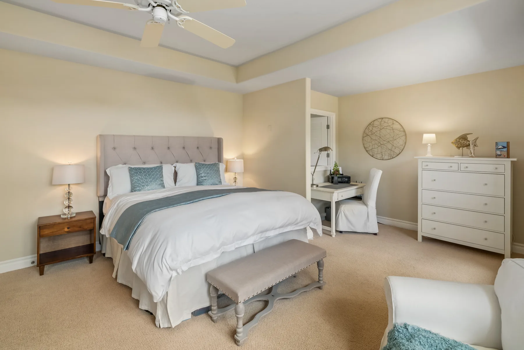 A bedroom with a neatly made bed, a bench, and a dresser.