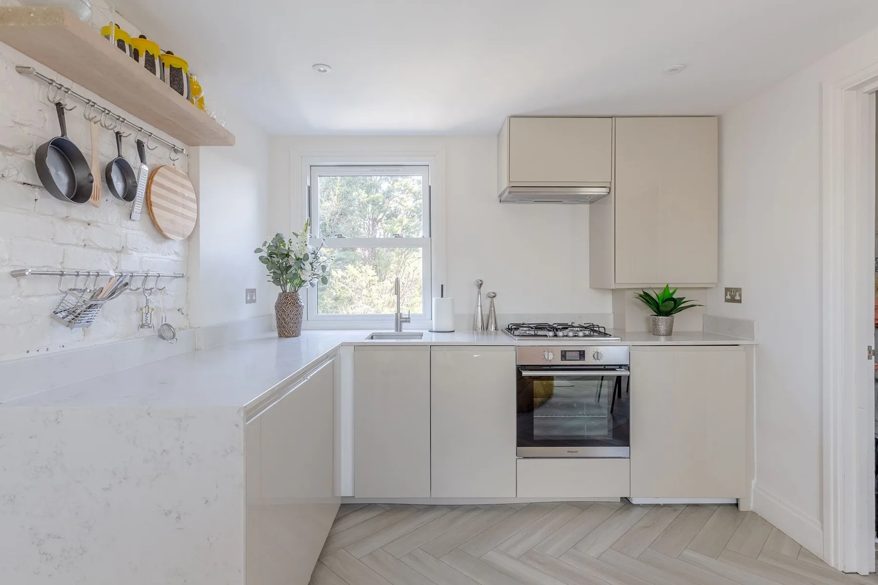 Una cocina luminosa con gabinetes blancos, una encimera y una ventana.