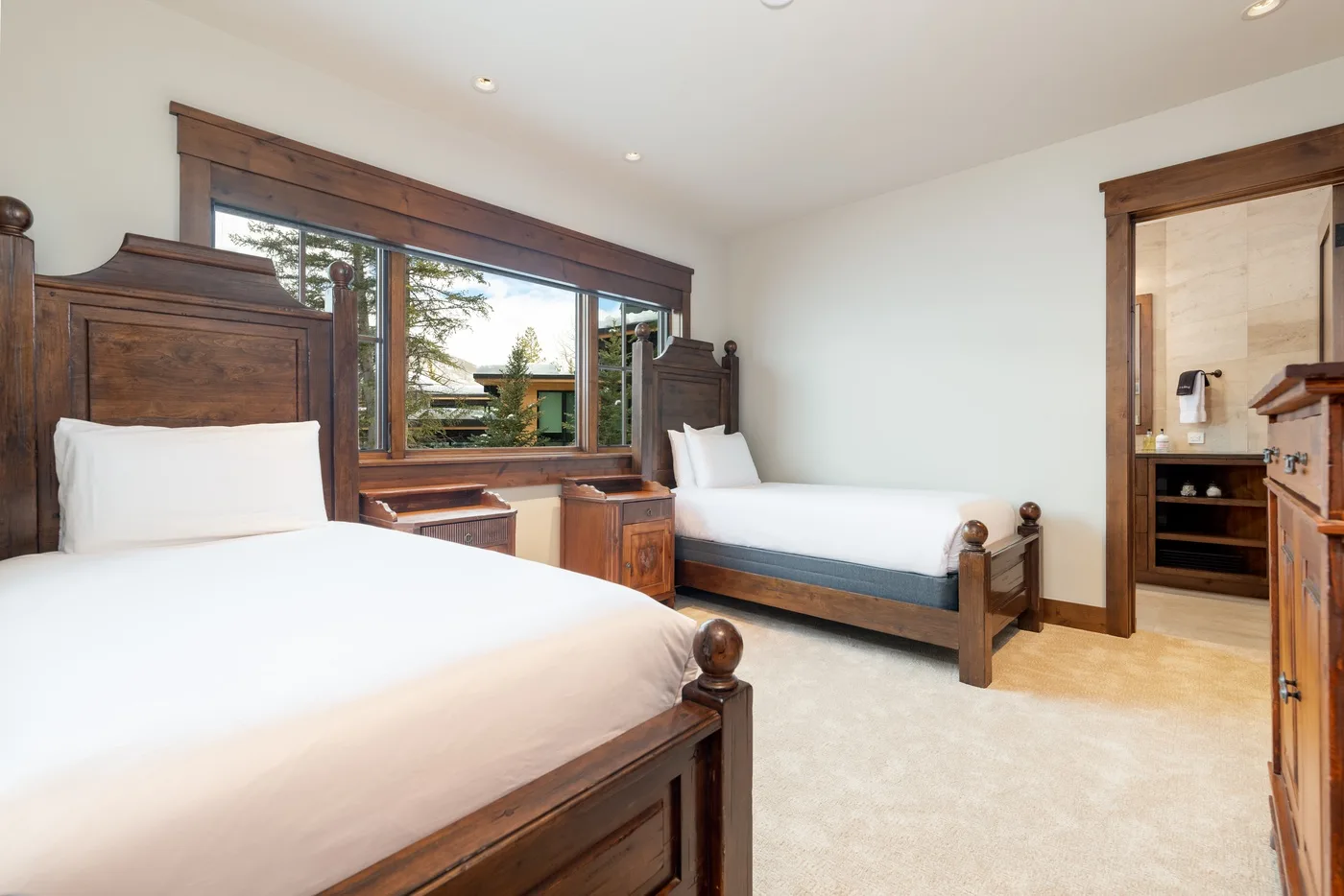 A bedroom with two beds and a large window.