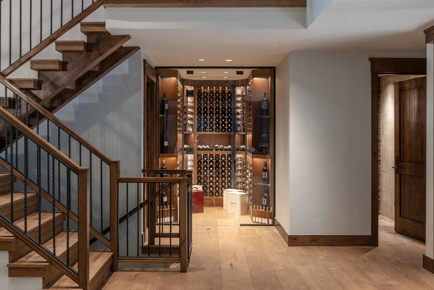 A wine cellar sits beneath a staircase in a spacious interior.