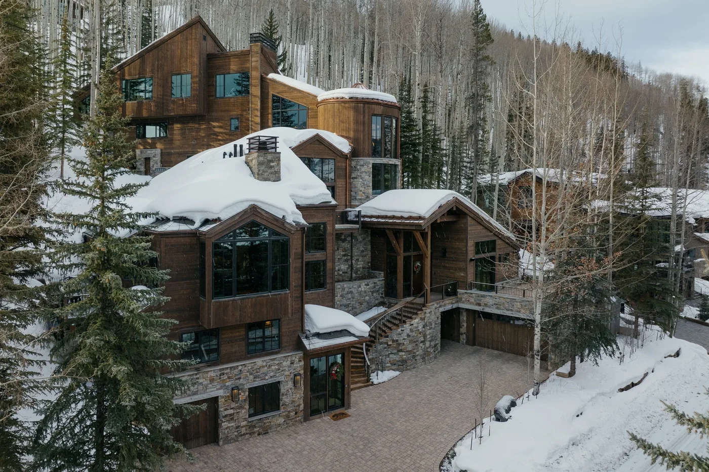 A large wood-and-stone building sits among trees in a snowy landscape.