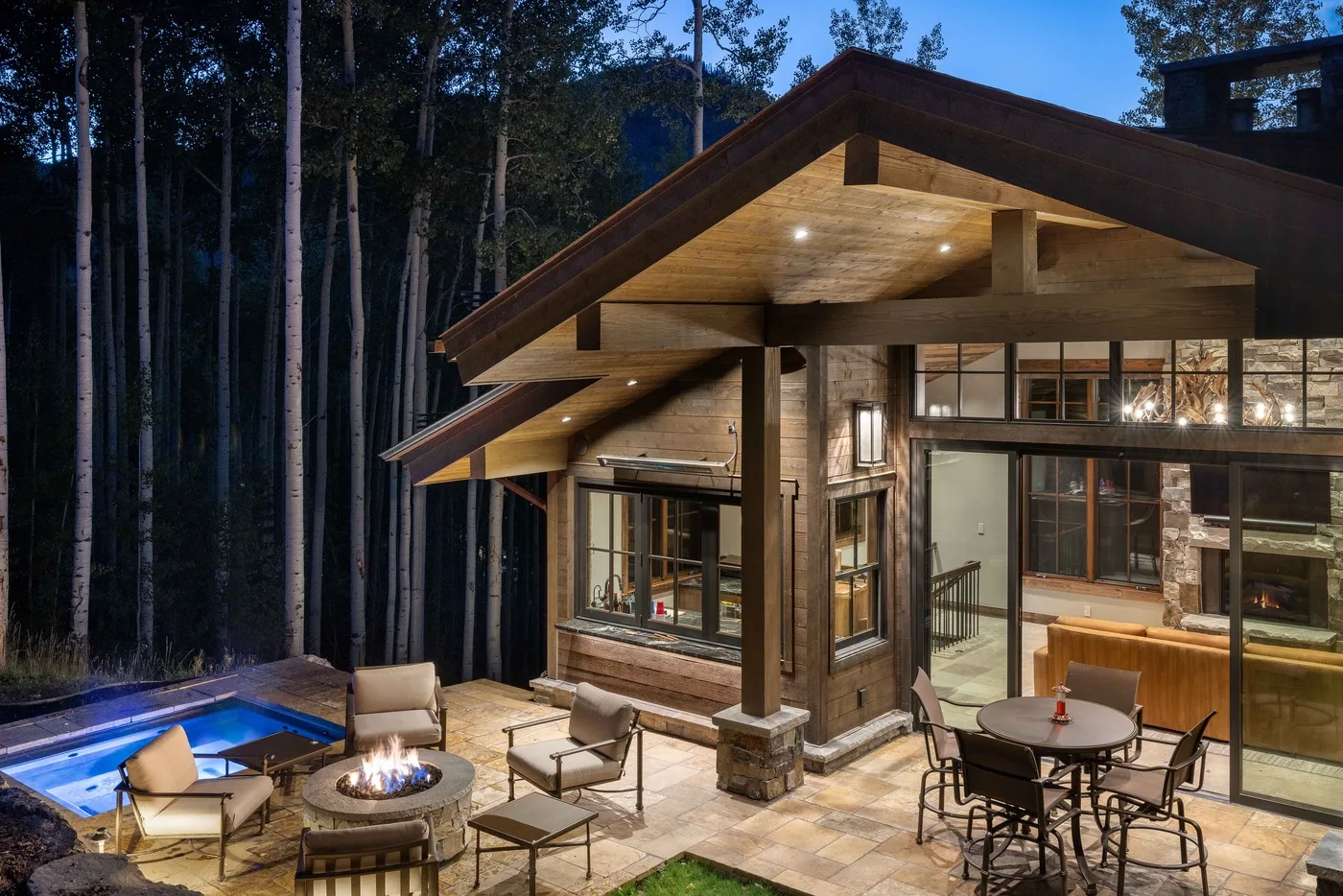 A wood-sided cabin opens onto a patio with a fire pit and outdoor seating.