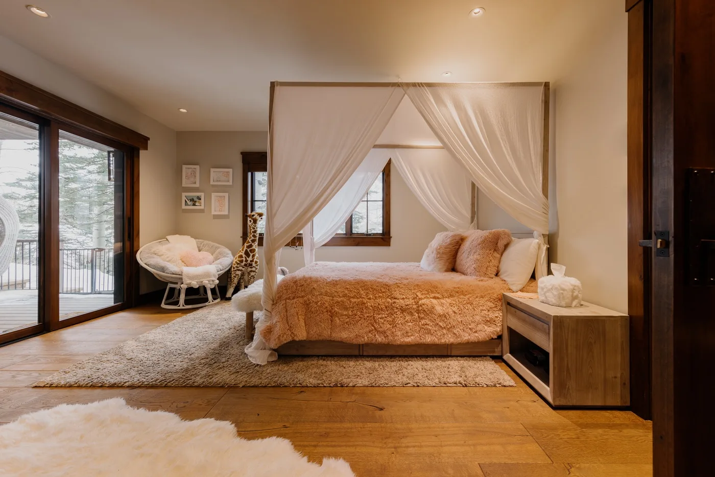 A bedroom with a canopy bed, a window, and glass doors opening to a balcony.