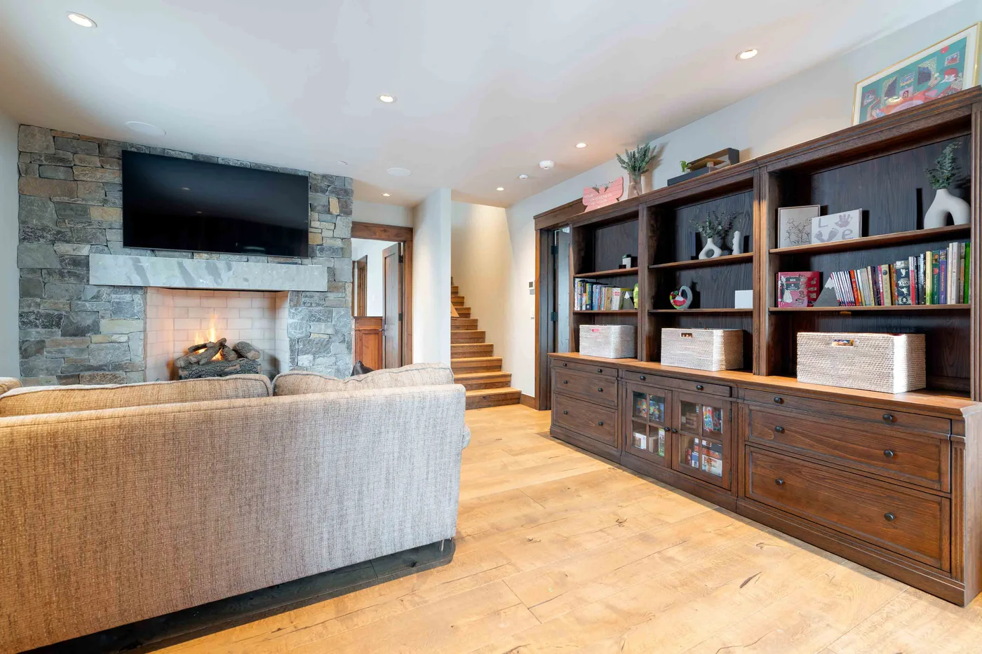 A living room with a stone fireplace and built-in wooden shelving.