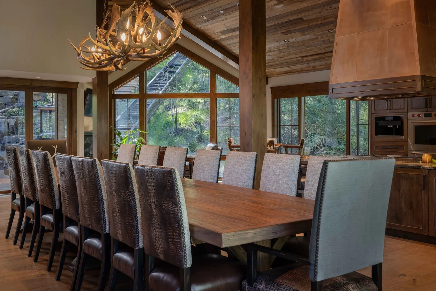 A spacious dining room with a long wooden table beneath a peaked timber ceiling.