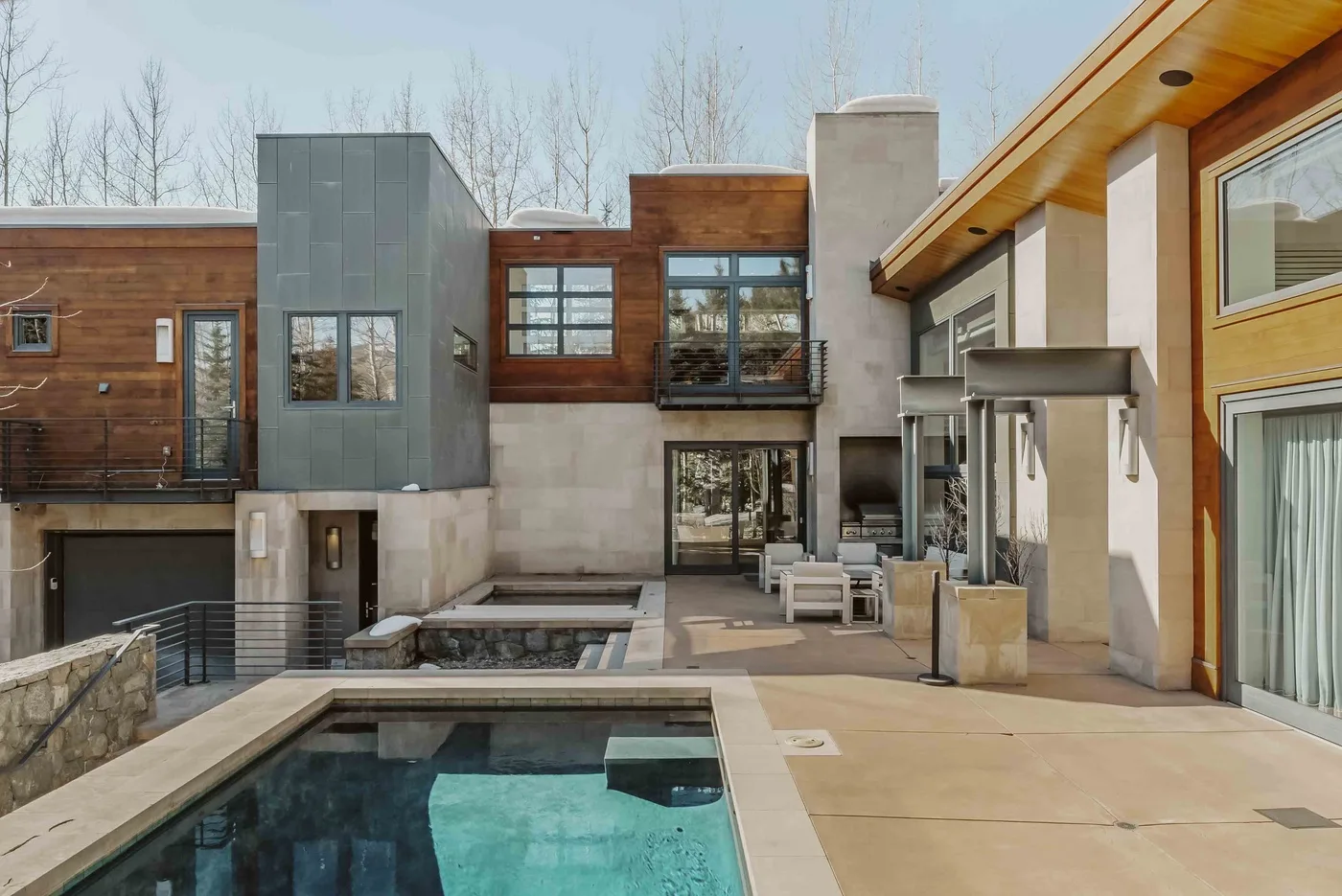 A modern patio surrounds a swimming pool beside a multi-story building.