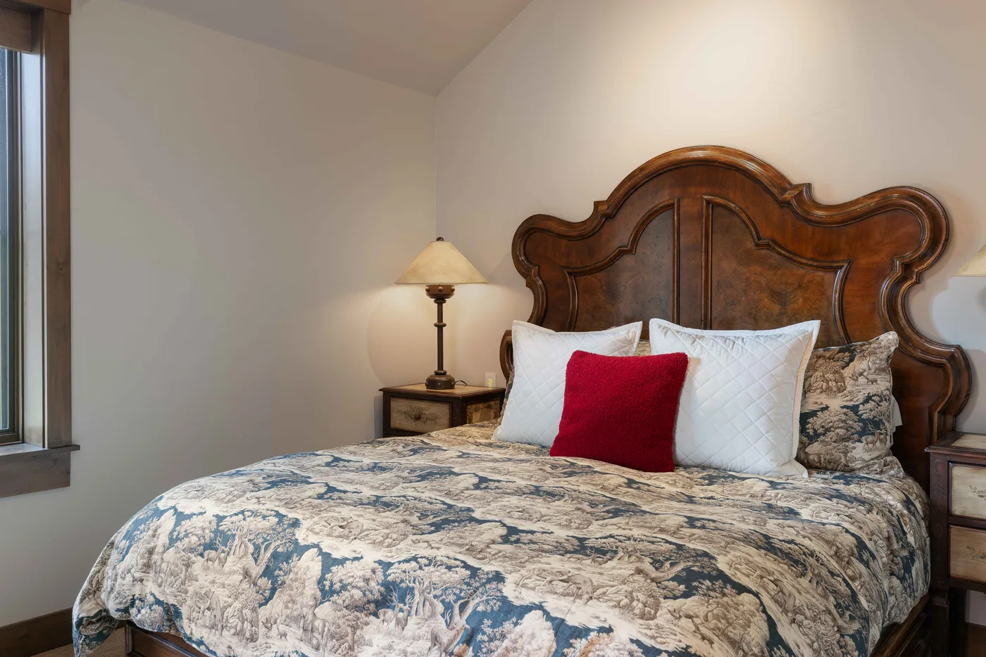 A bedroom with a bed dressed in patterned bedding and white pillows.