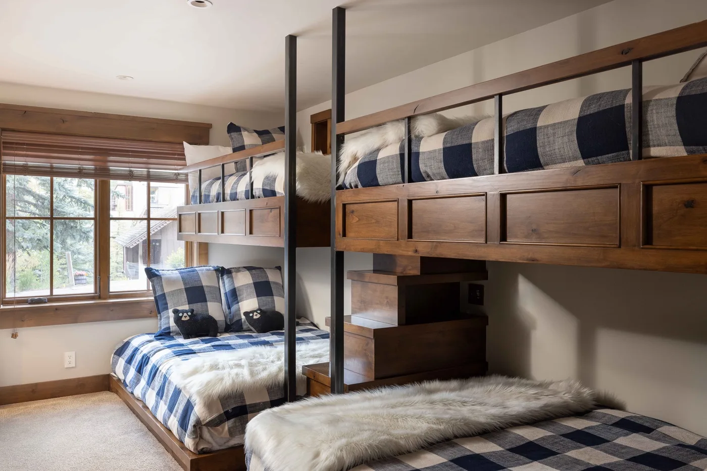 A bedroom with bunk beds, plaid bedding, and a large window.