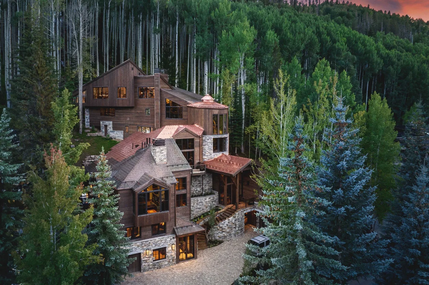 A large multi-level house nestled among dense evergreen trees.