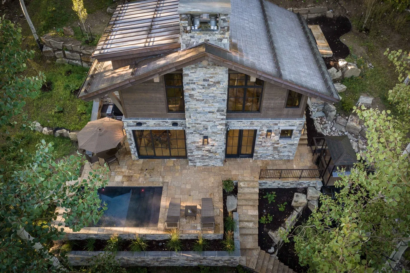 Aerial view of a stone house with a paved patio and outdoor seating.