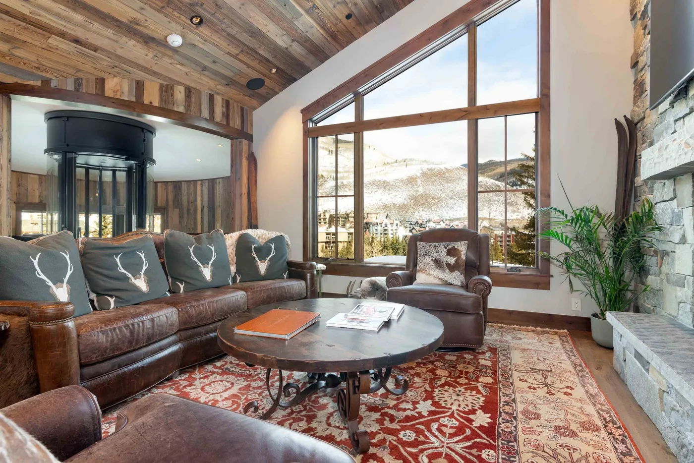 A living room with leather seating, a coffee table, and large windows overlooking a snowy landscape.