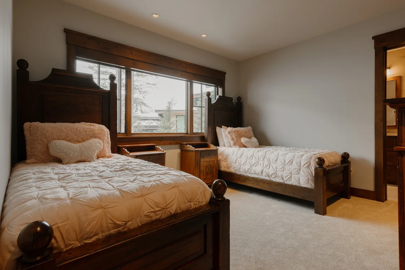 A bedroom with two beds, quilted bedding, and a large window.