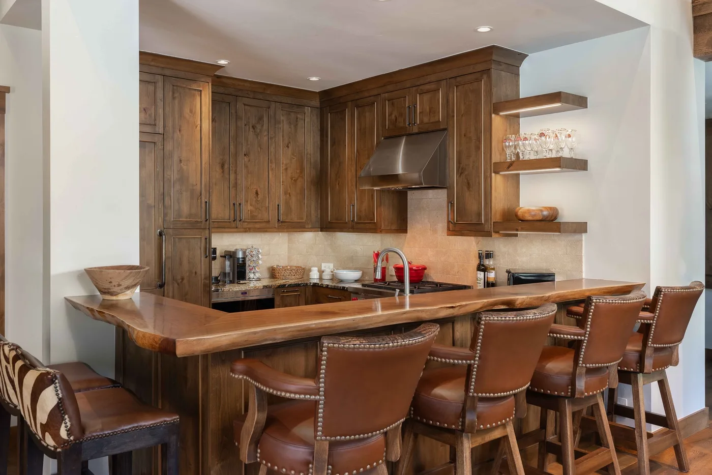 A kitchen with dark wood cabinets, a wide counter, and bar seating.