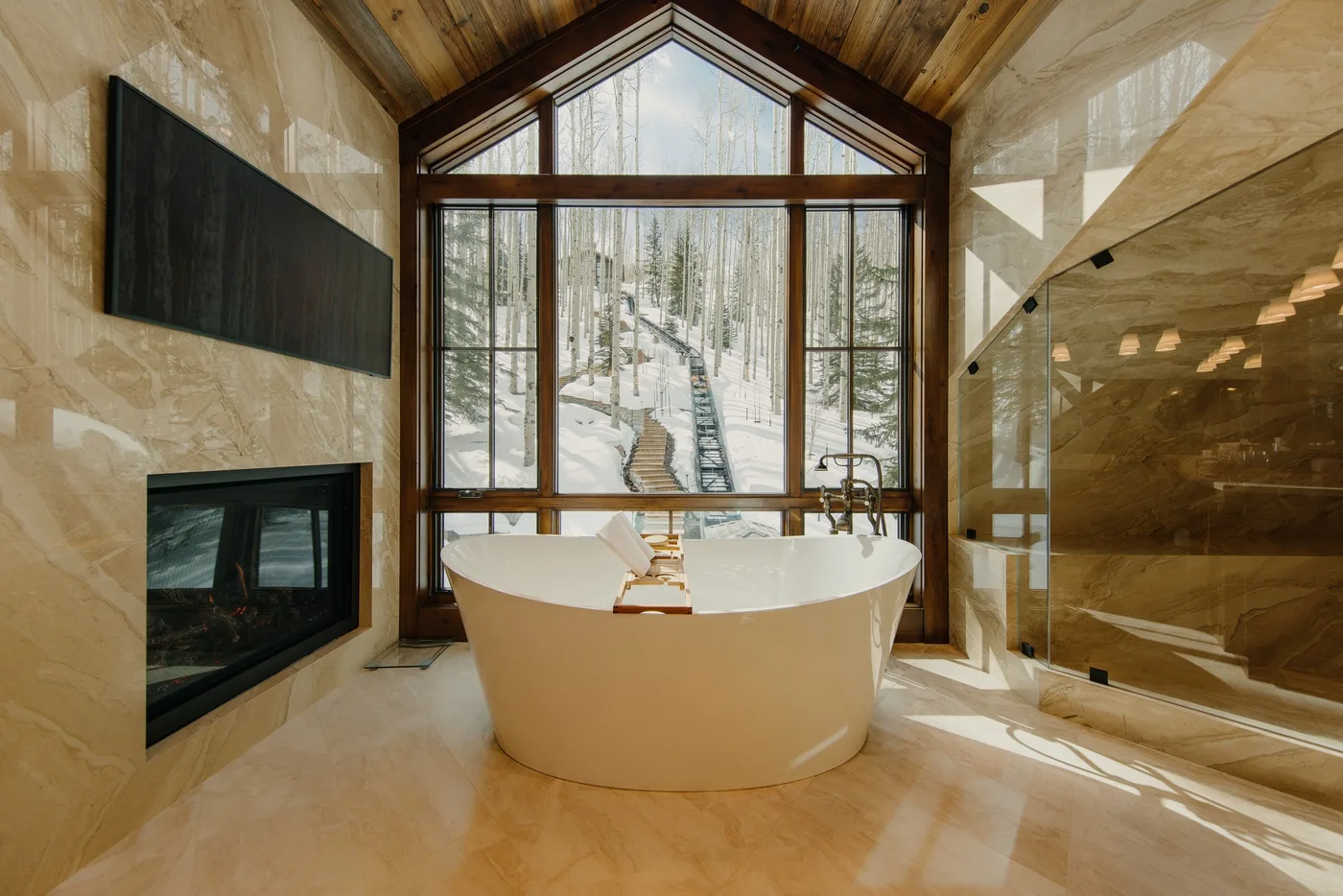 A freestanding bathtub sits before a large window in a bright bathroom.