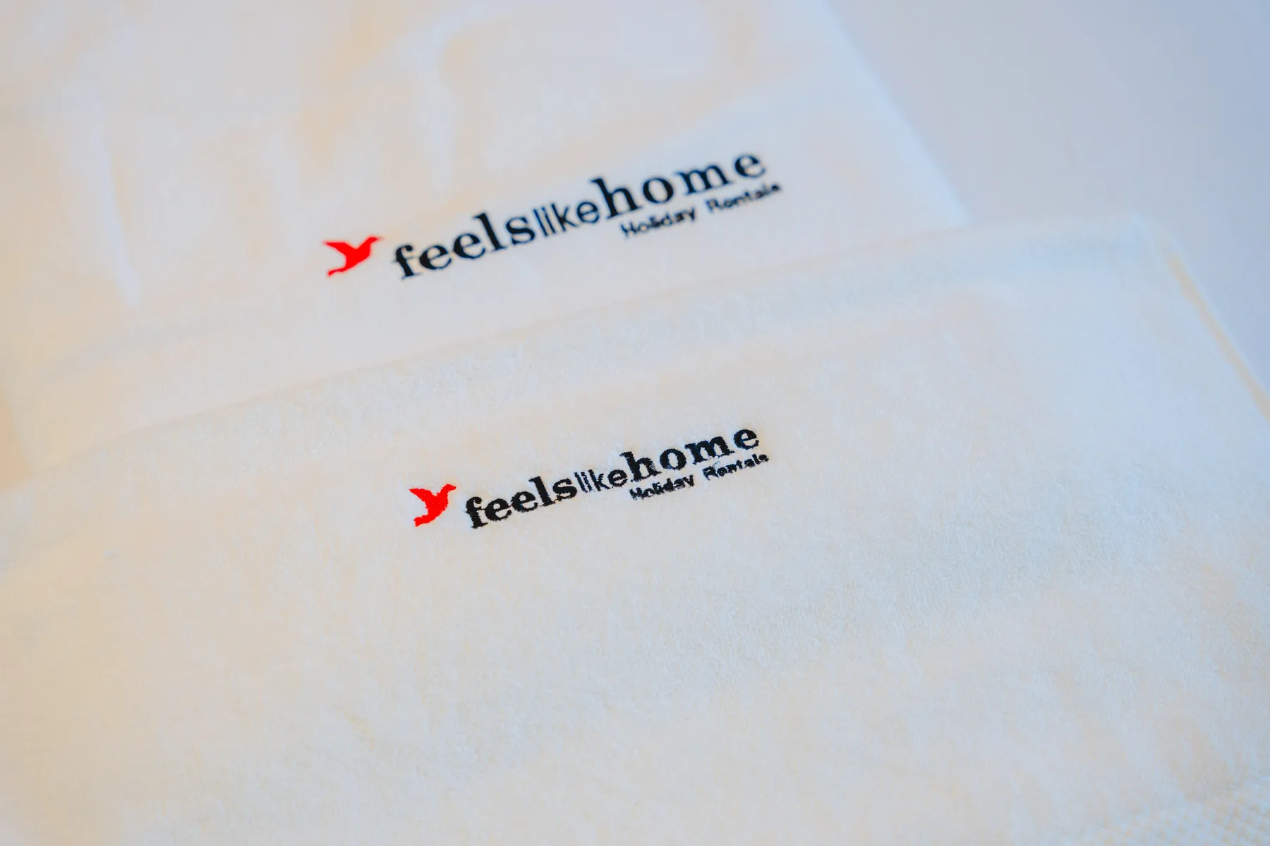 Toallas blancas con logotipos impresos están colocadas sobre una cama.