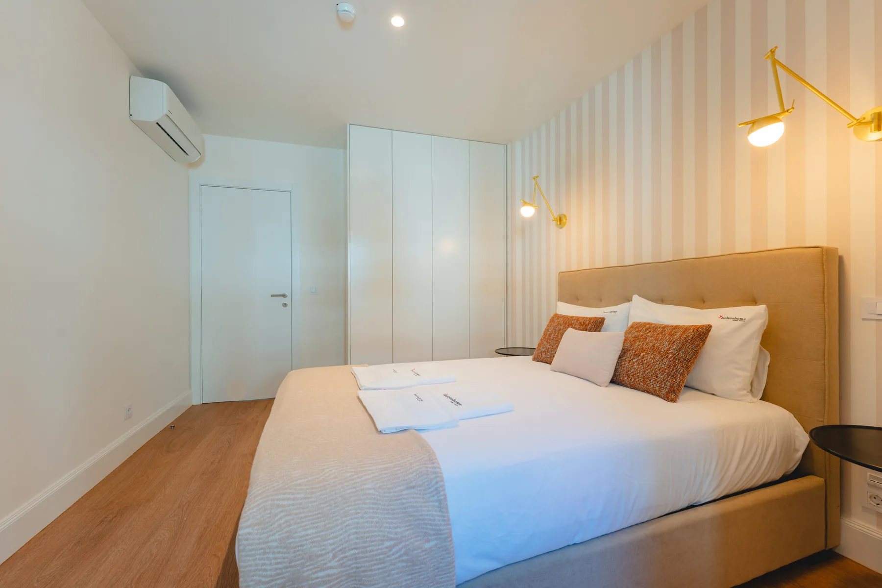 Un dormitorio con una cama bien hecha y papel pintado a rayas.