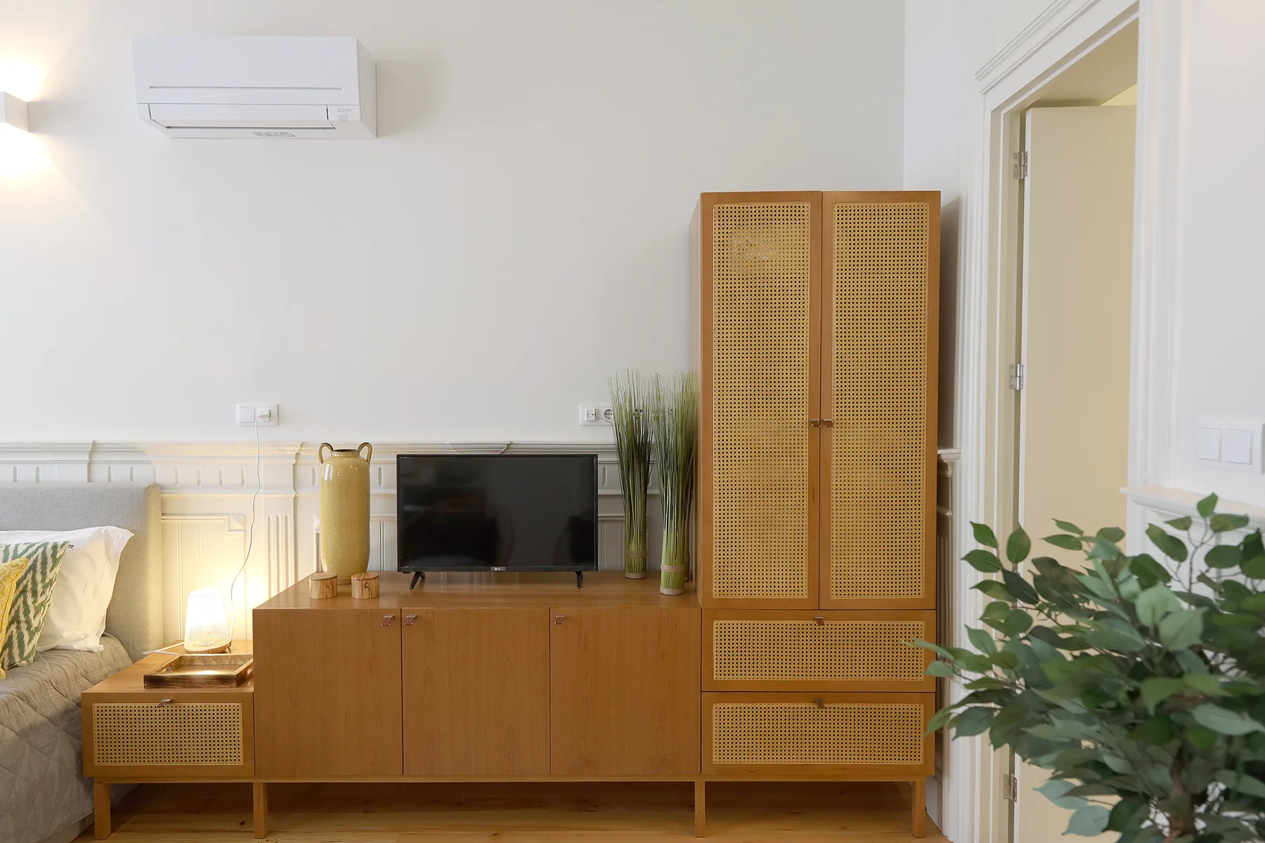 A living room with a sofa, television, and wooden storage cabinet.