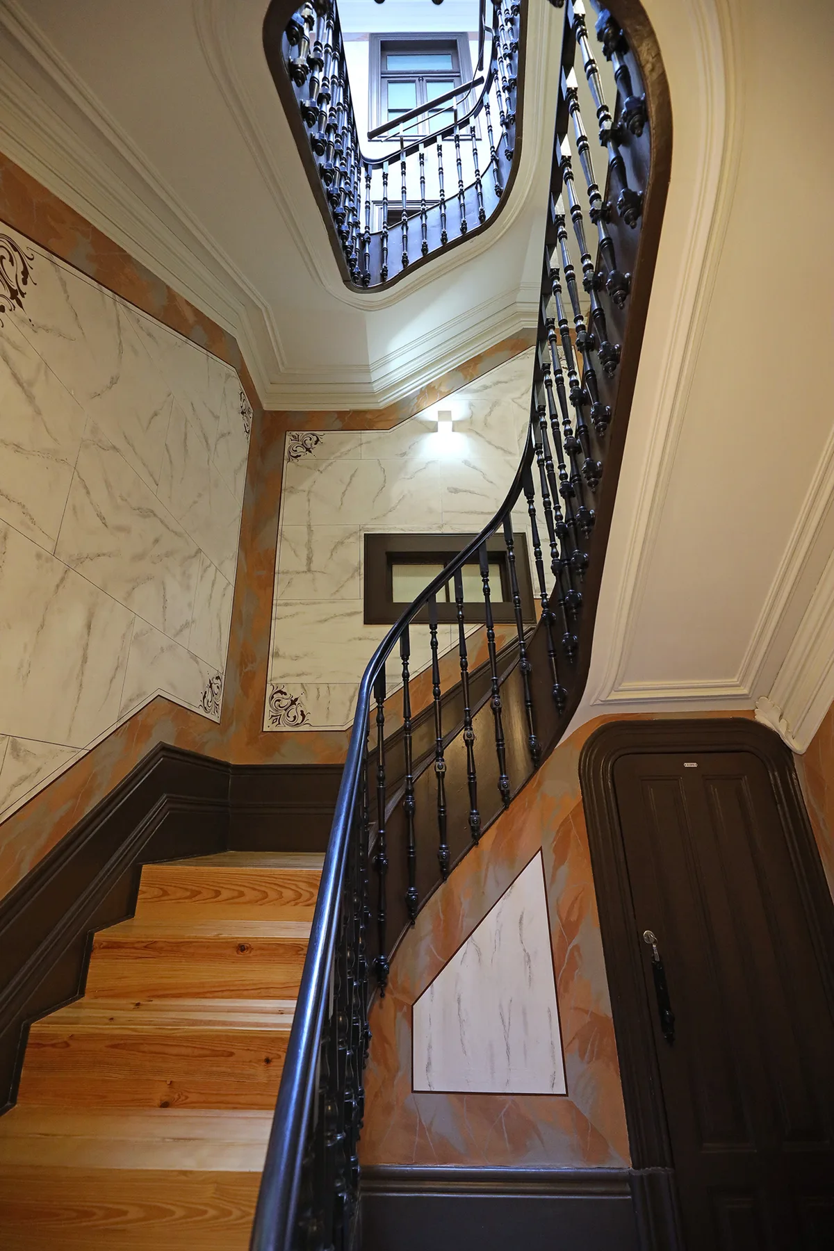 An indoor staircase with wooden steps and ornate dark railings.