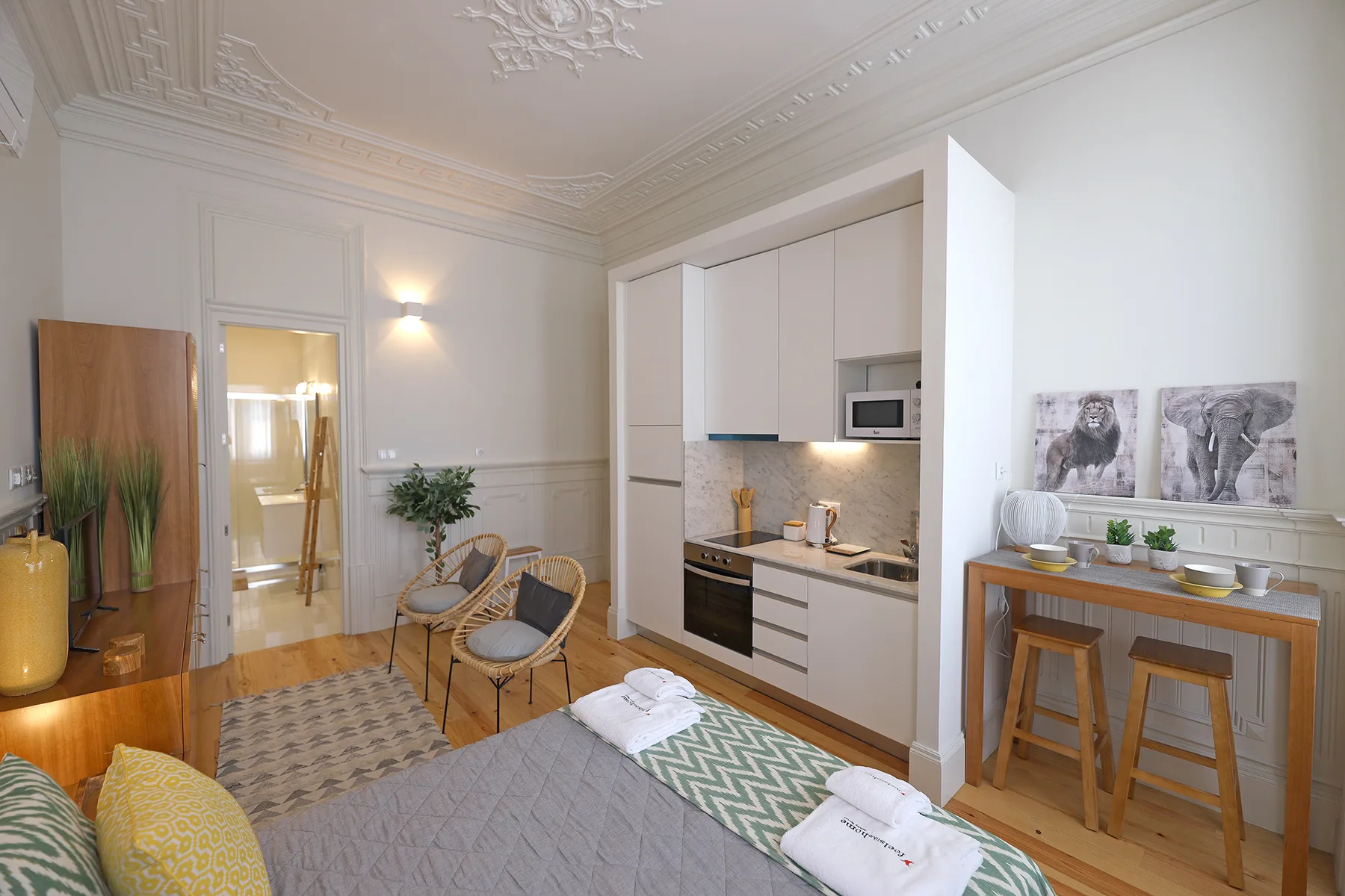 A studio room with a bed, seating, and a compact kitchen.