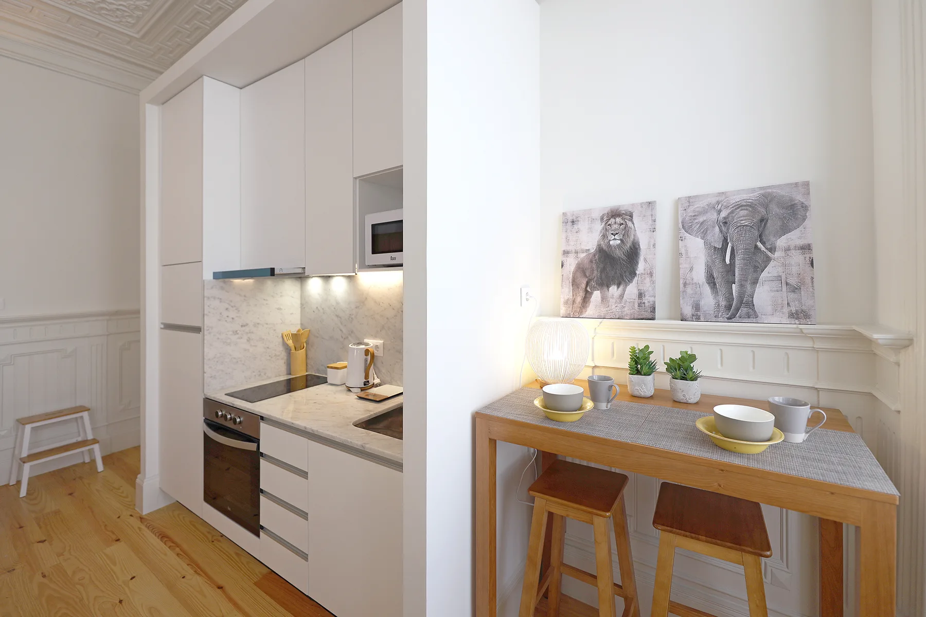 A bright studio interior with a compact kitchen and a wooden dining table.