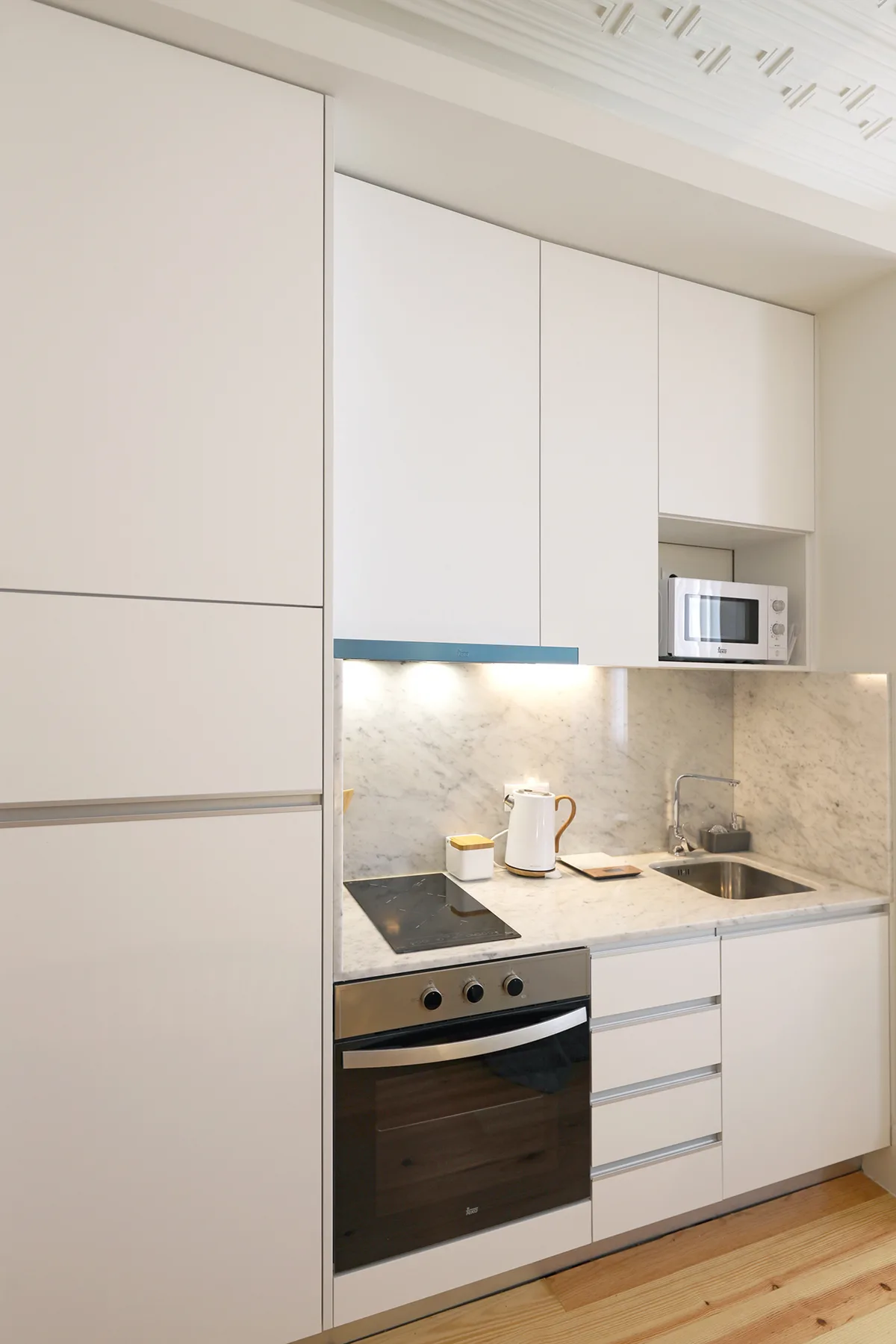 A modern kitchen with white cabinets, a countertop, and built-in appliances.