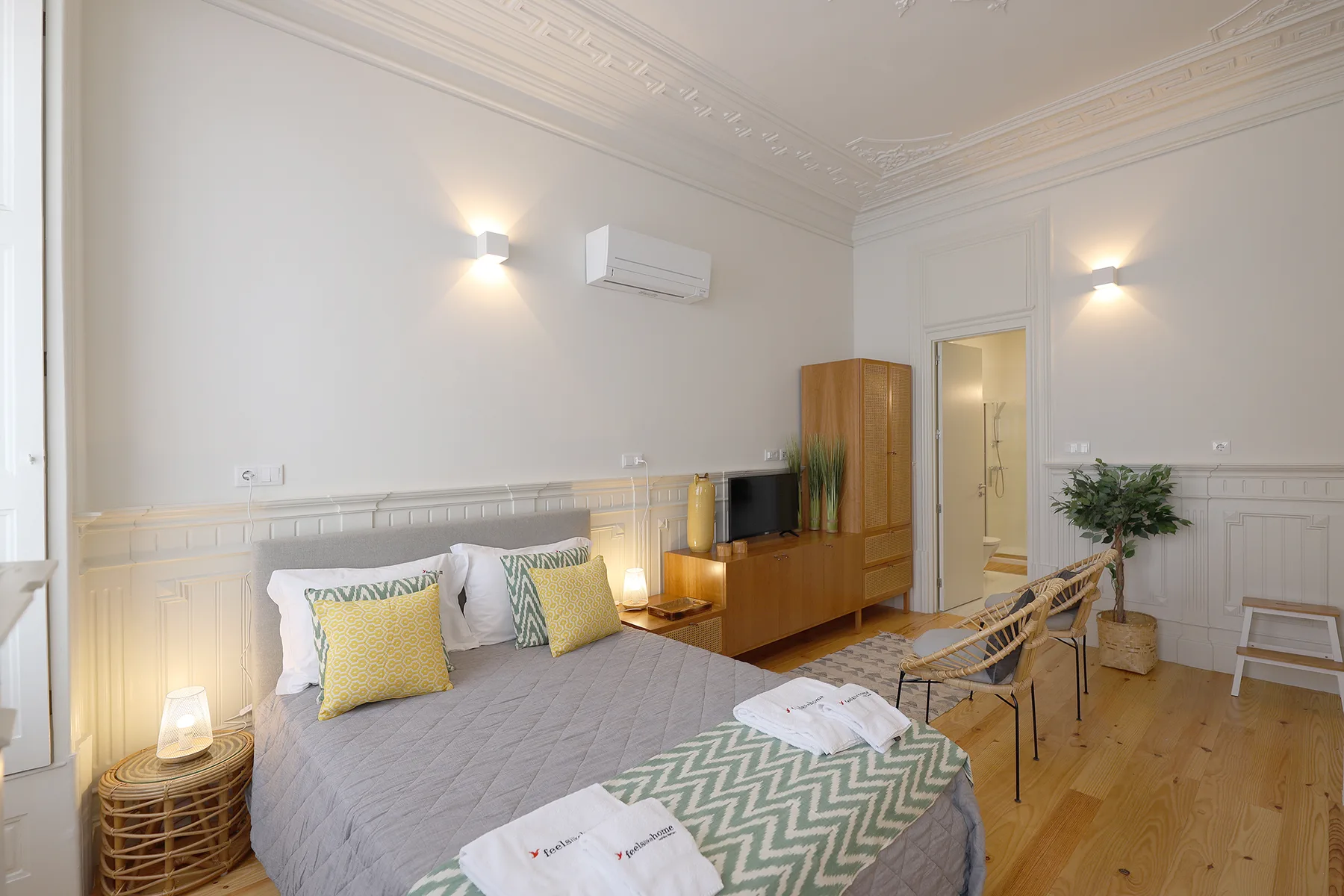 A bedroom with a double bed, bedside tables, and a wooden media cabinet.