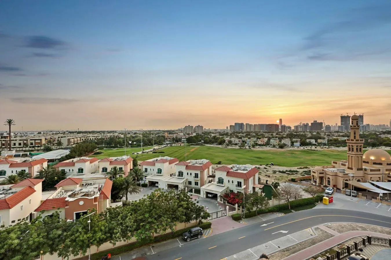 A residential neighborhood stretches toward the city skyline at sunset.