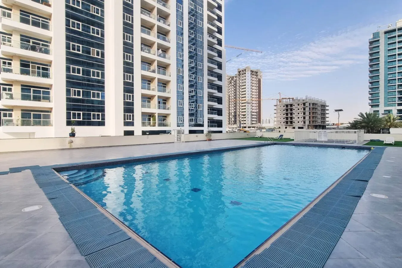 A swimming pool sits among modern high-rise apartment buildings.