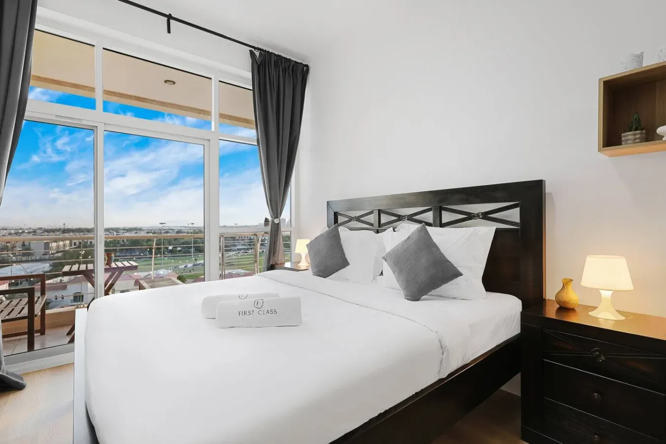 A bright bedroom with a neatly made bed beside a large window.