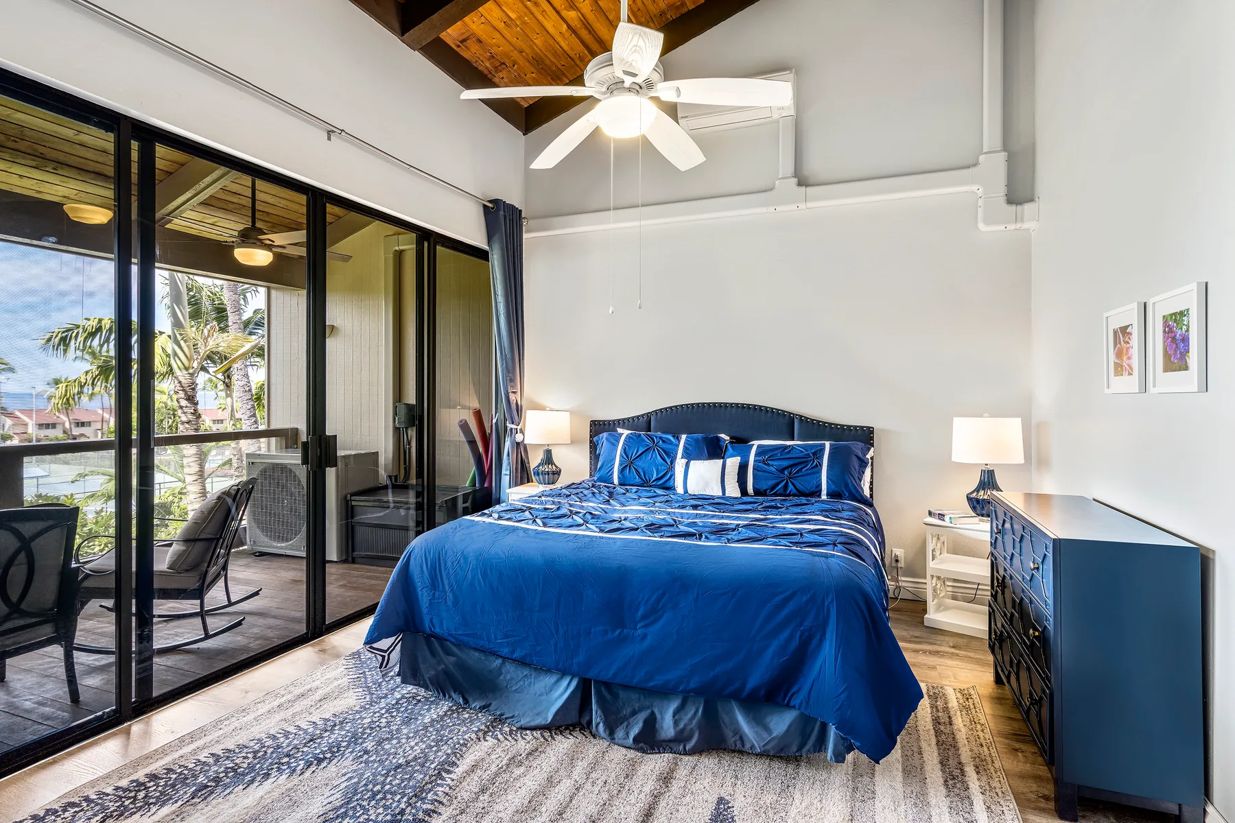 A bedroom with a blue bed, bedside tables, and glass doors opening onto a balcony.