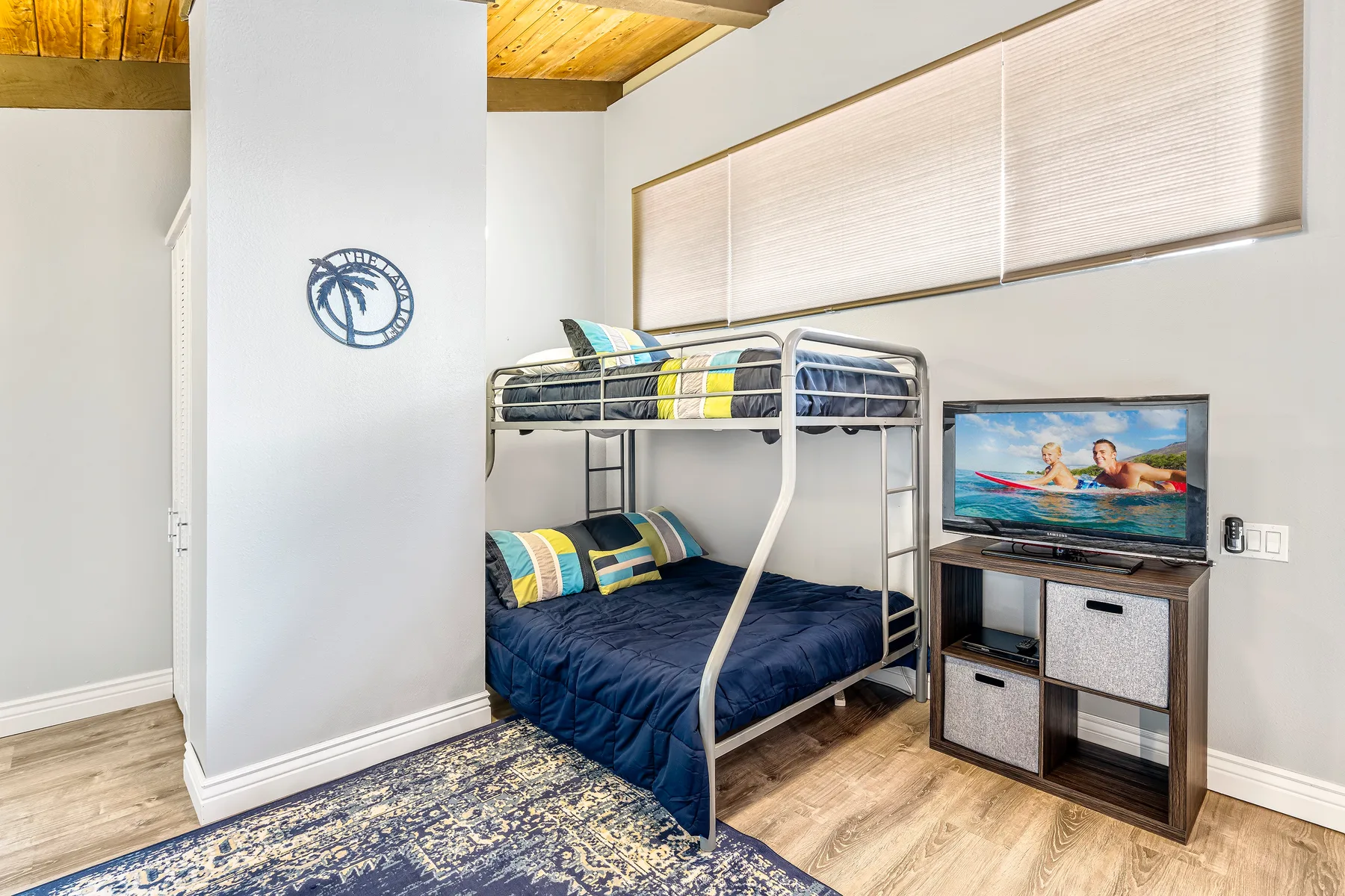 A bedroom with a metal bunk bed, colorful bedding, and a television.