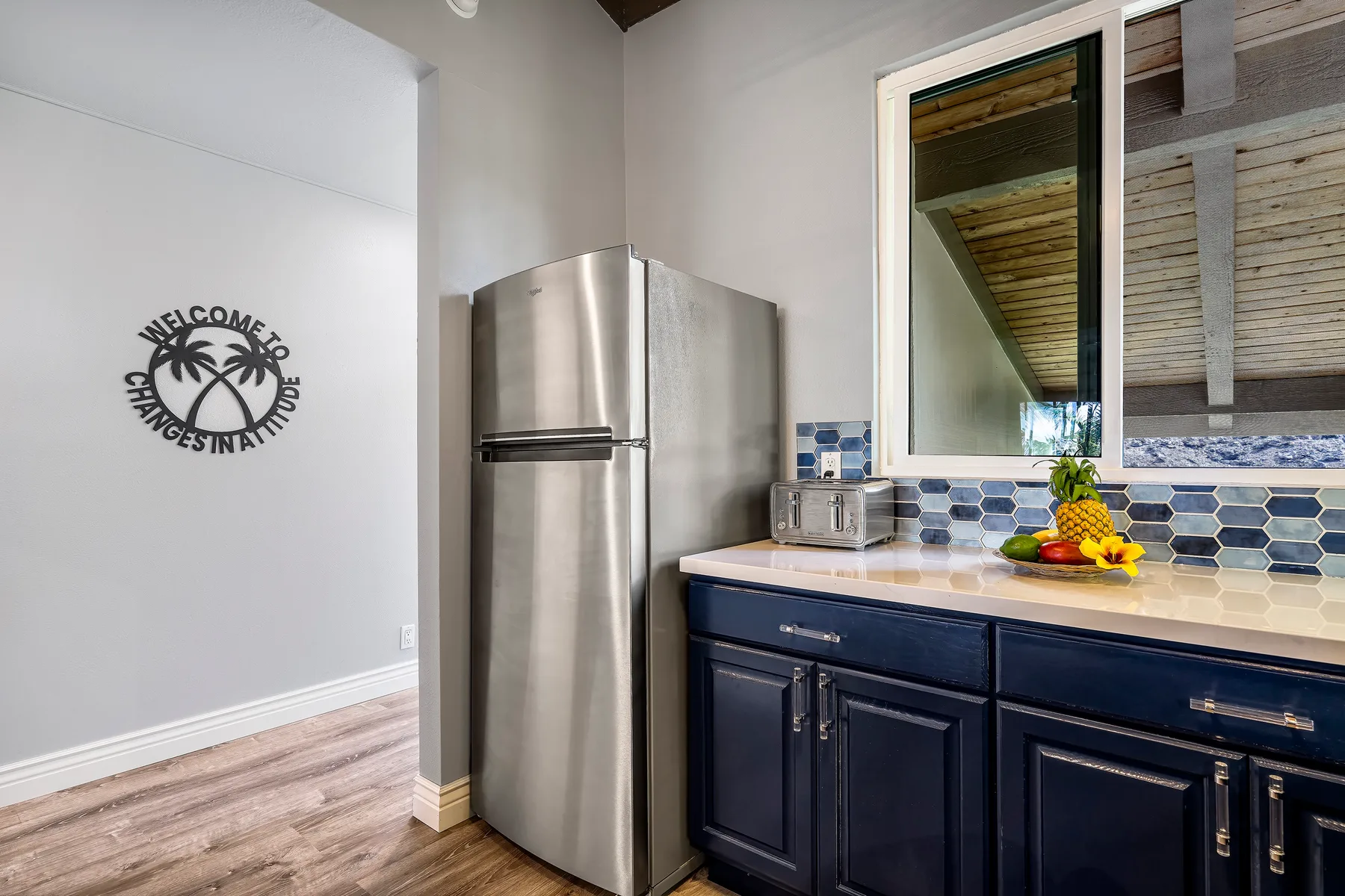 A kitchen with dark cabinets, a stainless steel refrigerator, and a tiled backsplash.
