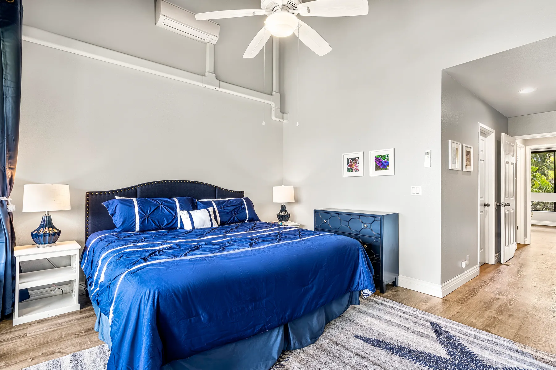 A bedroom with blue bedding, bedside tables, and a ceiling fan.
