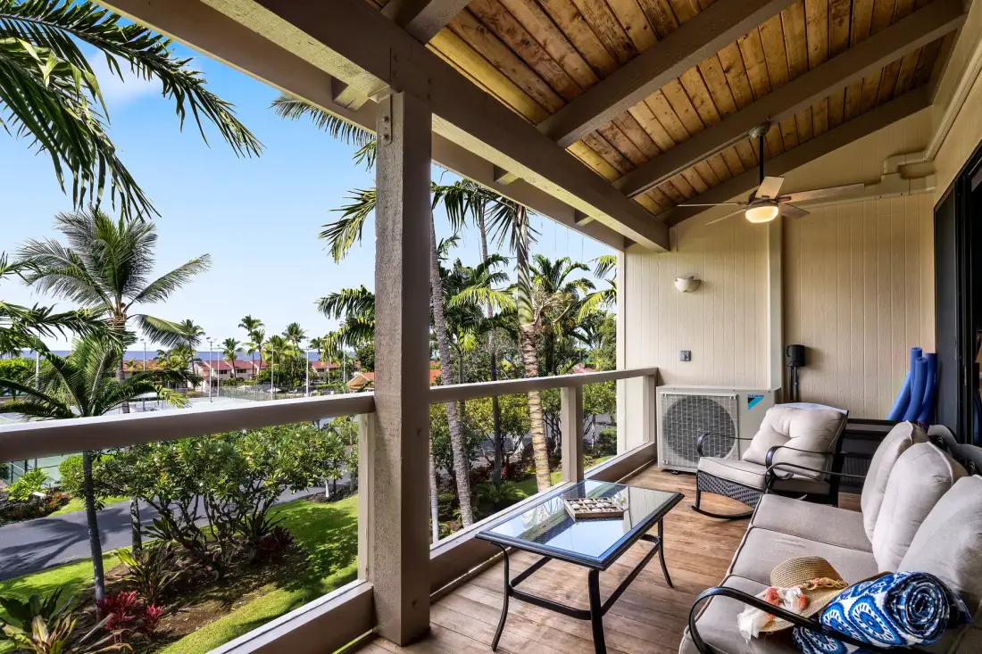 A covered outdoor seating area overlooks palm trees and greenery.