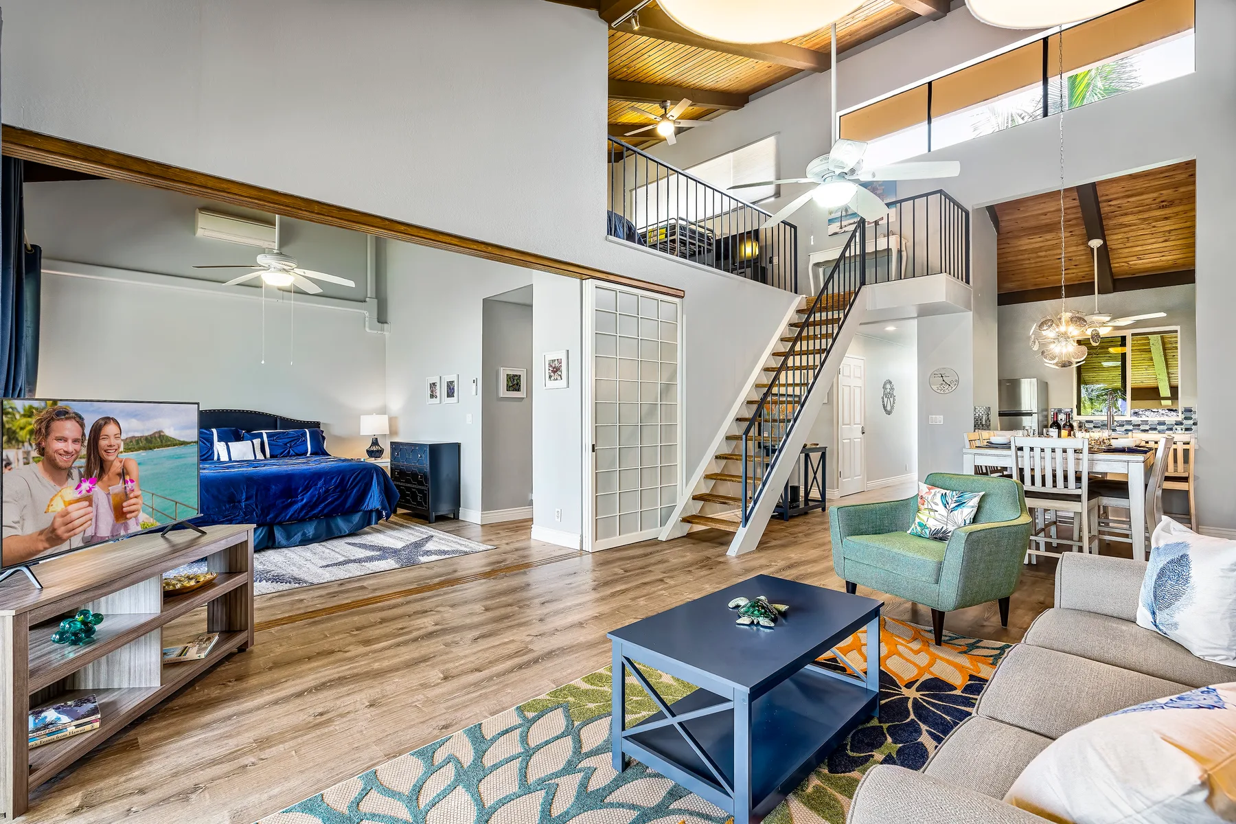 A spacious living area with a television, seating, and a staircase to an upper level.