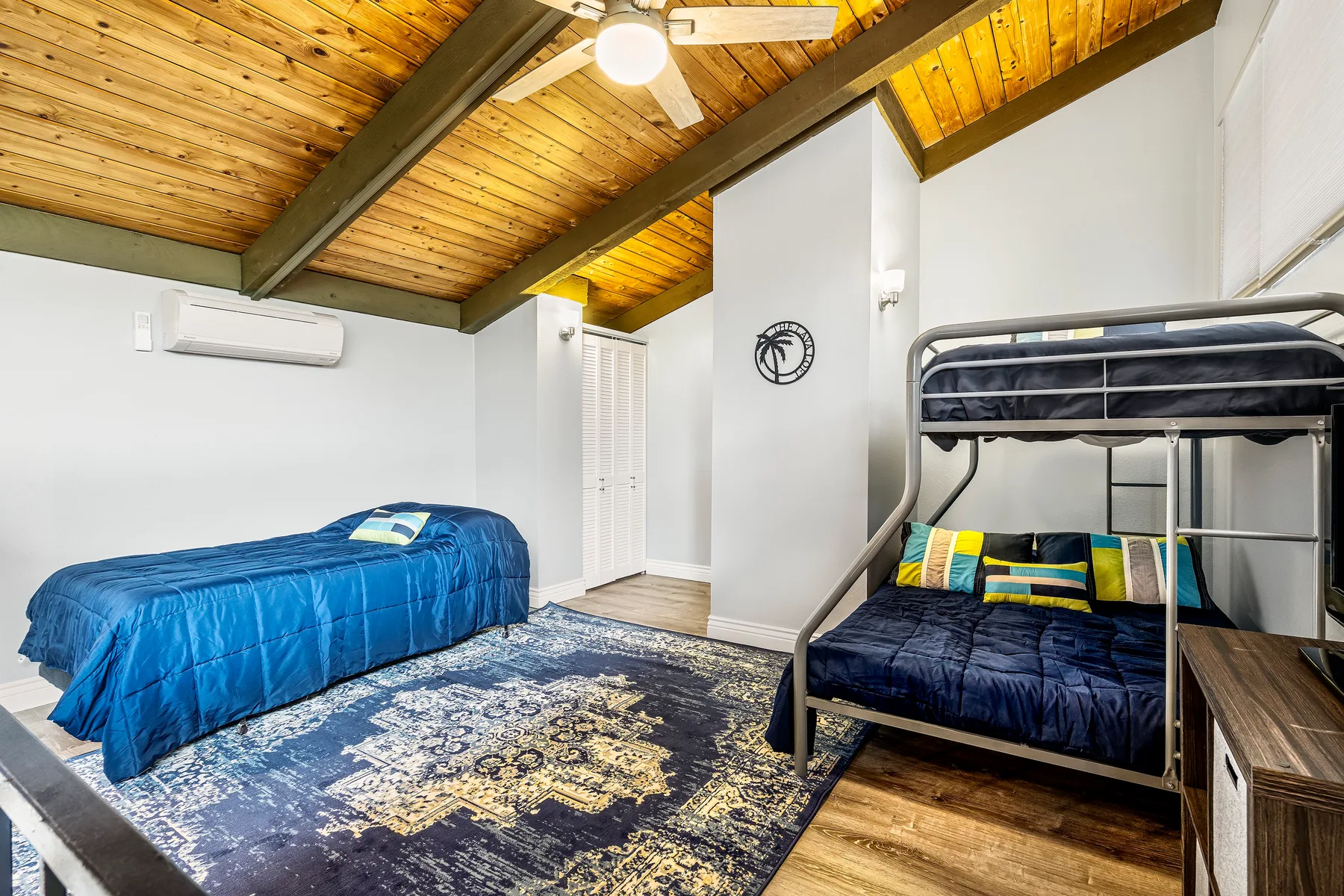 A bedroom with a single bed, a bunk bed, and a patterned rug.