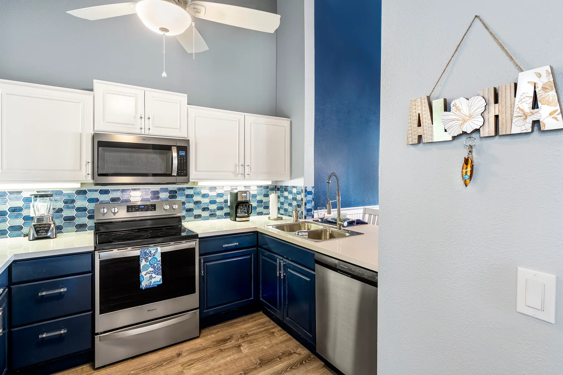 A modern kitchen with dark blue cabinets, stainless steel appliances, and a tiled backsplash.