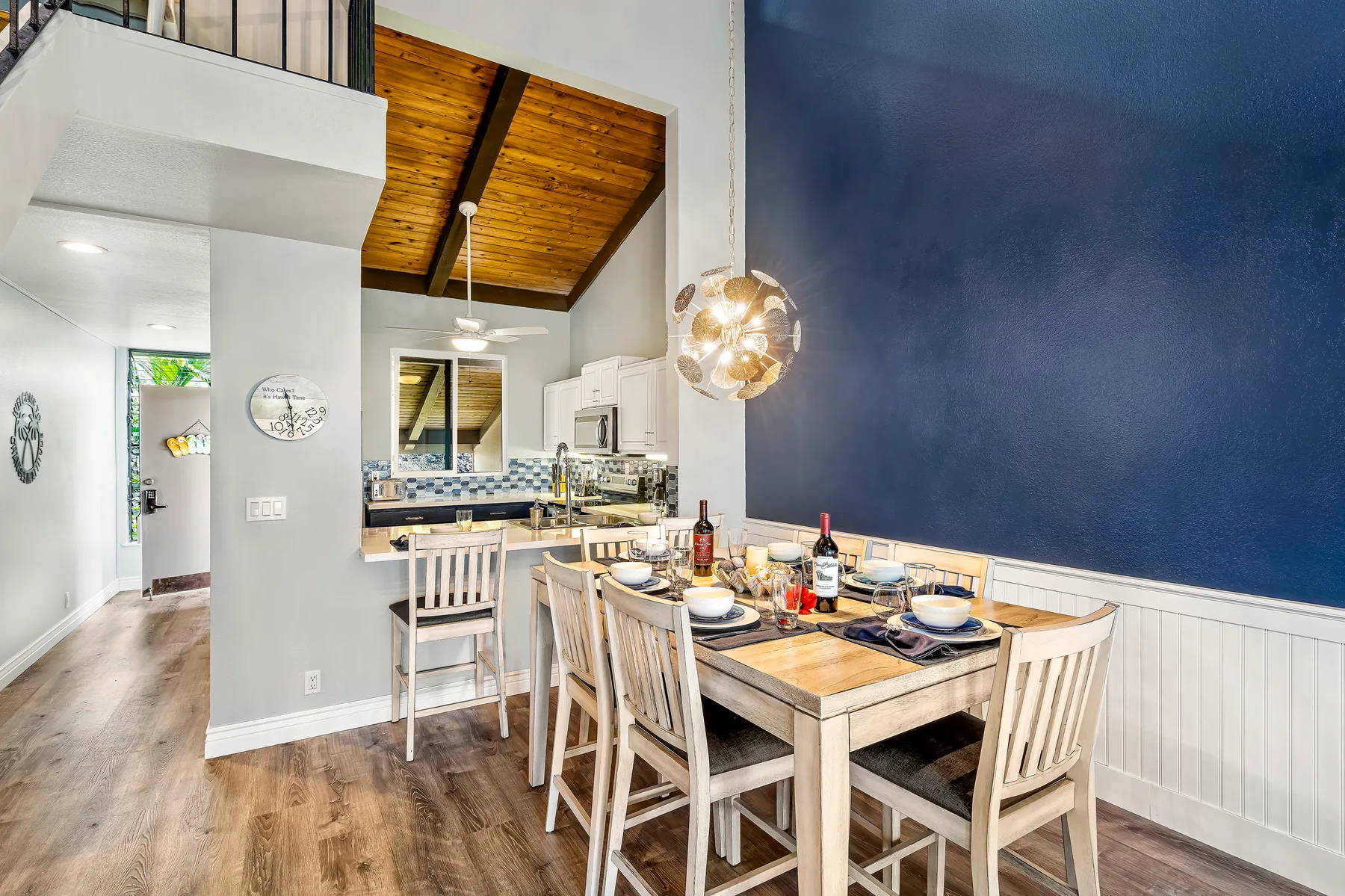 A dining area with a set table sits beside an open kitchen.