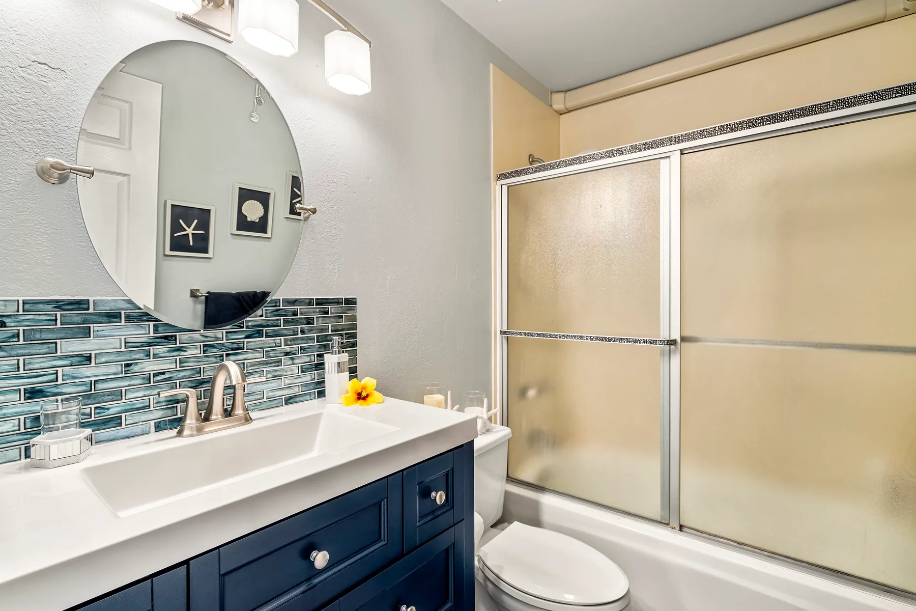 A bathroom with a vanity, round mirror, and shower.