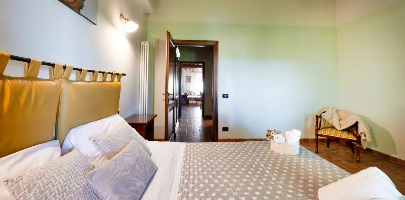 A bedroom with a patterned bedspread and an open doorway.