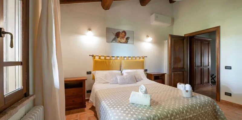 A bedroom with a double bed, bedside tables, and a wooden wardrobe.