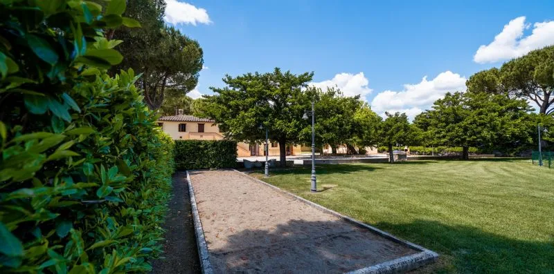 A landscaped outdoor park has a gravel path, open lawn, and mature trees.