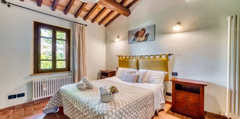 A bedroom with a double bed, bedside tables, and a window.