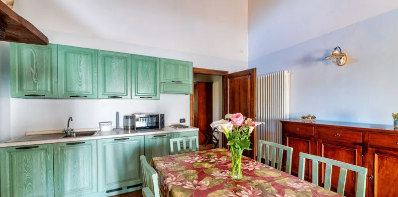 A kitchen and dining area with green cabinets and a flower centerpiece on the table.